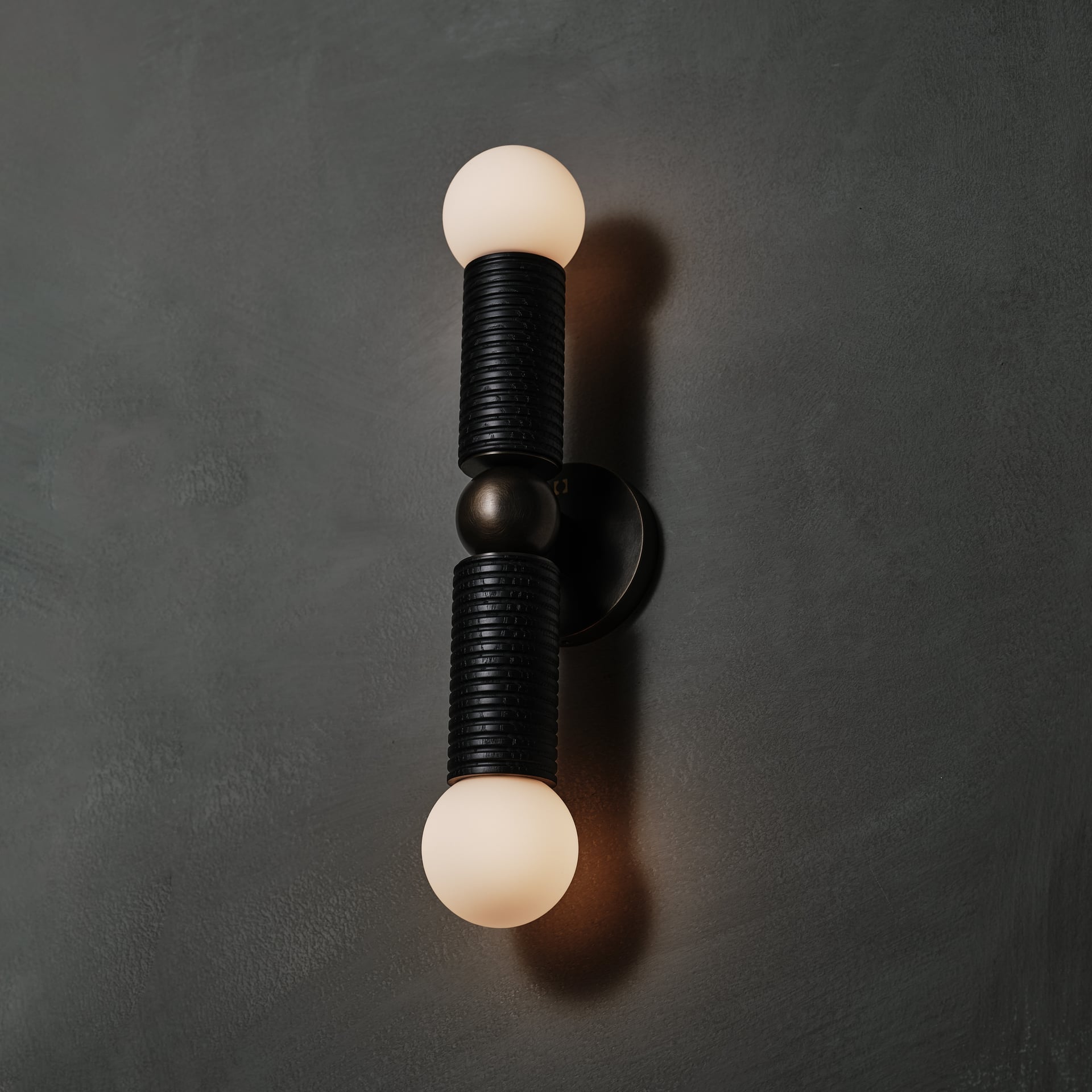 Axis Wall Sconce in ebonized and brown wax polished, angled view, lit, Studio Baldo