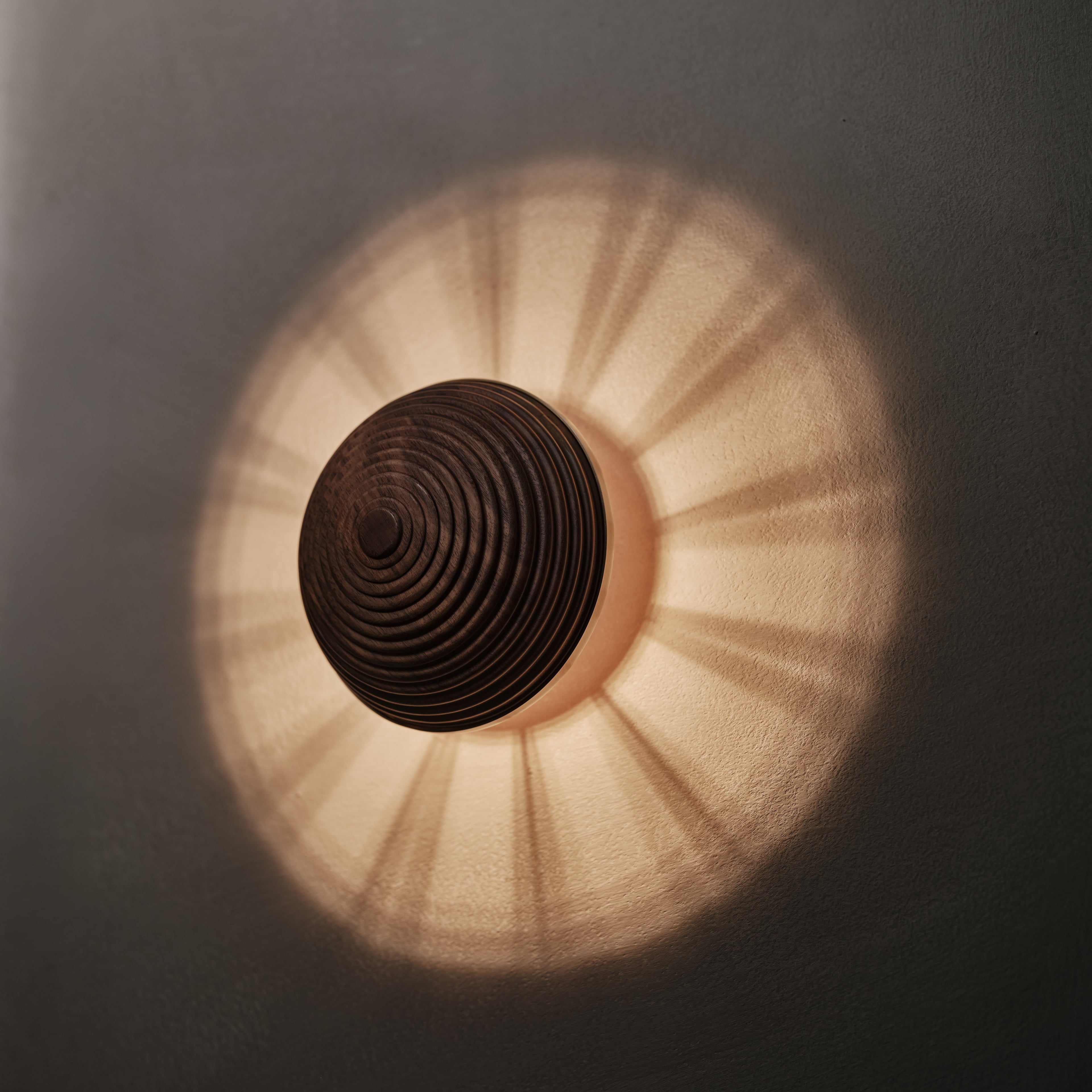 Contour Wall Sconce in walnut and aged brass, angled view, lit, Studio Baldo